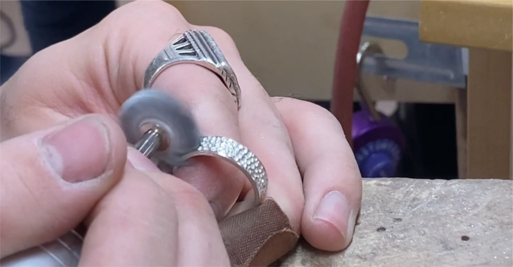 image of a silver ring being polished by hand using a flex shaft rotary tool