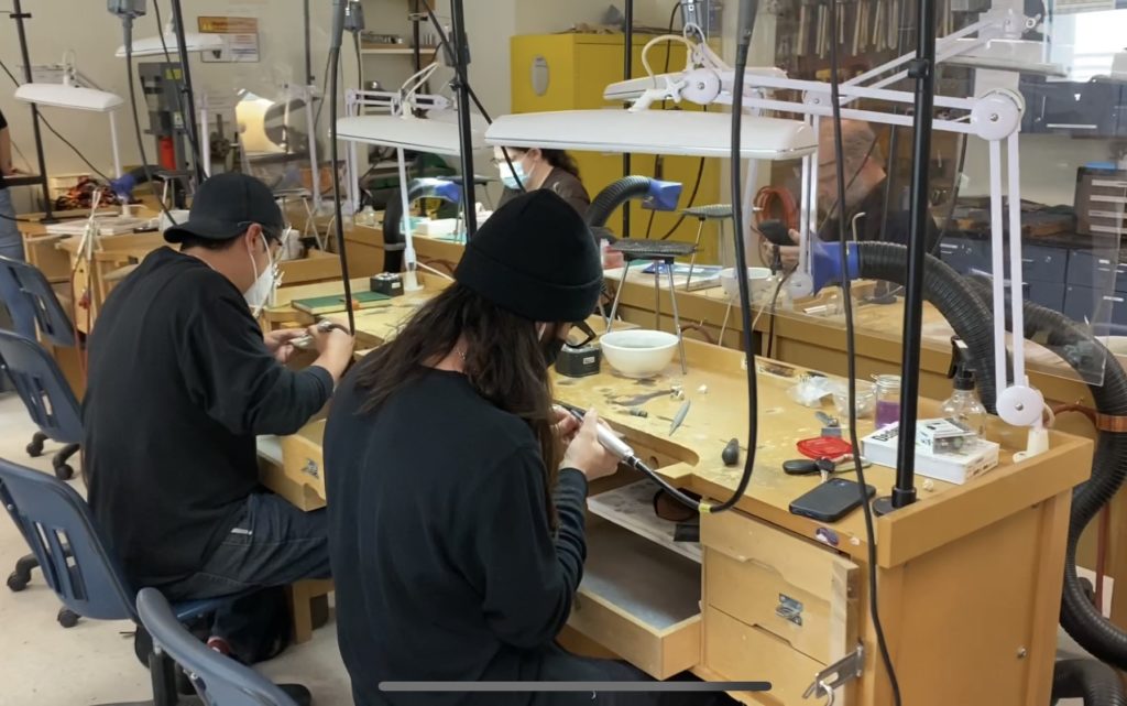 image of a bench jewelry studio. Pictured are students working at benches
